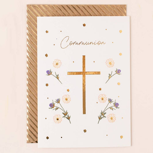 A white greeting card with a gold foil cross in the centre, surrounded by flowers with a gold striped envelope.  The word communion is shown above the cross.