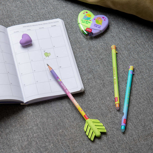 Colorful stationery items including a notebook, pencils, and erasers on a gray surface.