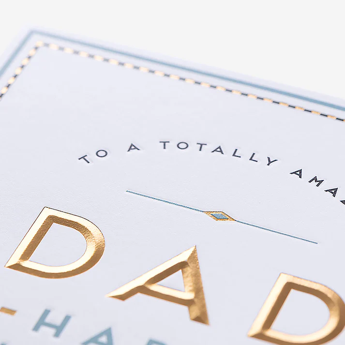 Greeting card with gold text 'To a totally amazing dad' on a light blue background