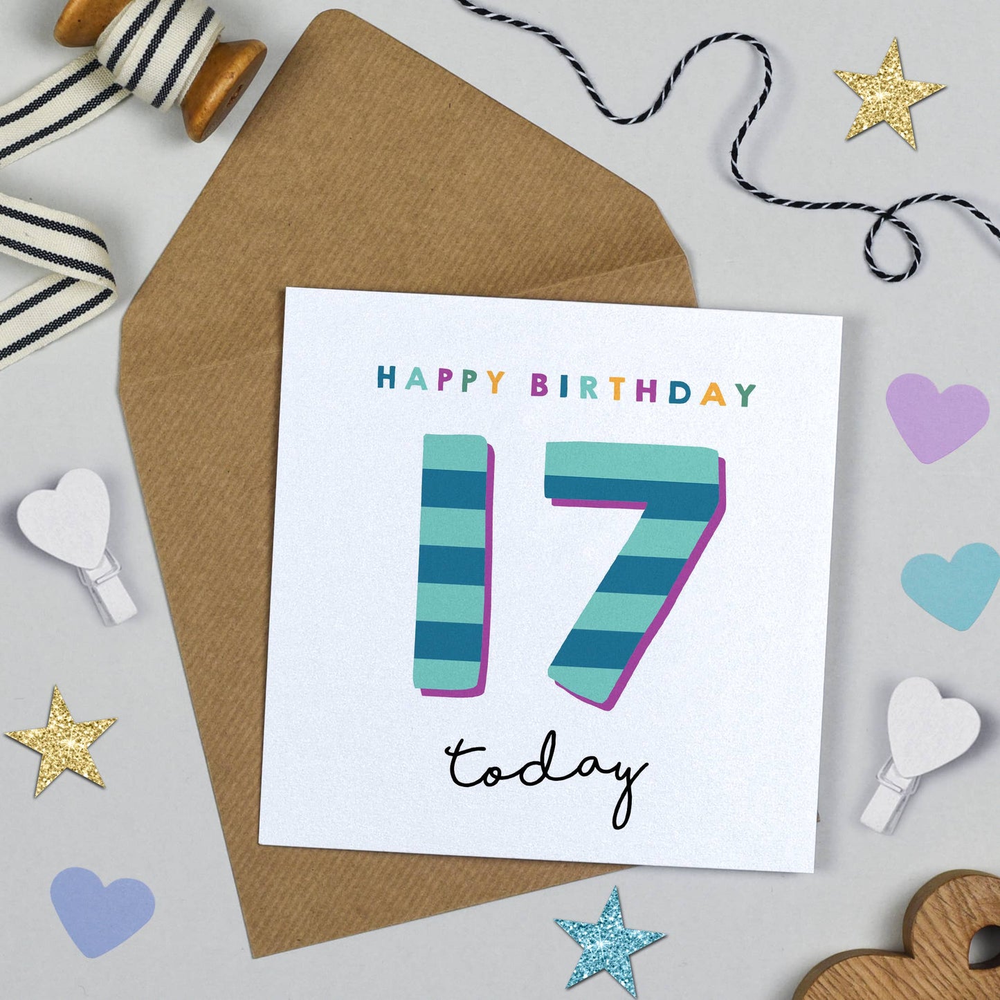 Birthday card with colorful number 17 on a white background with decorative items around.
