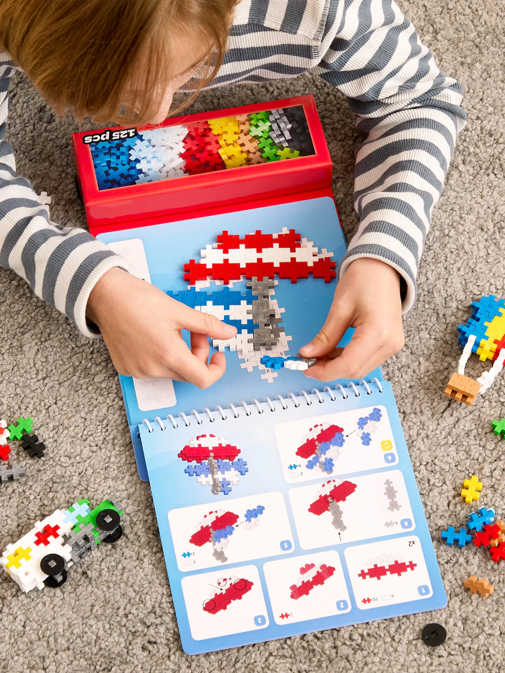 Child playing with a building block book on the floor
