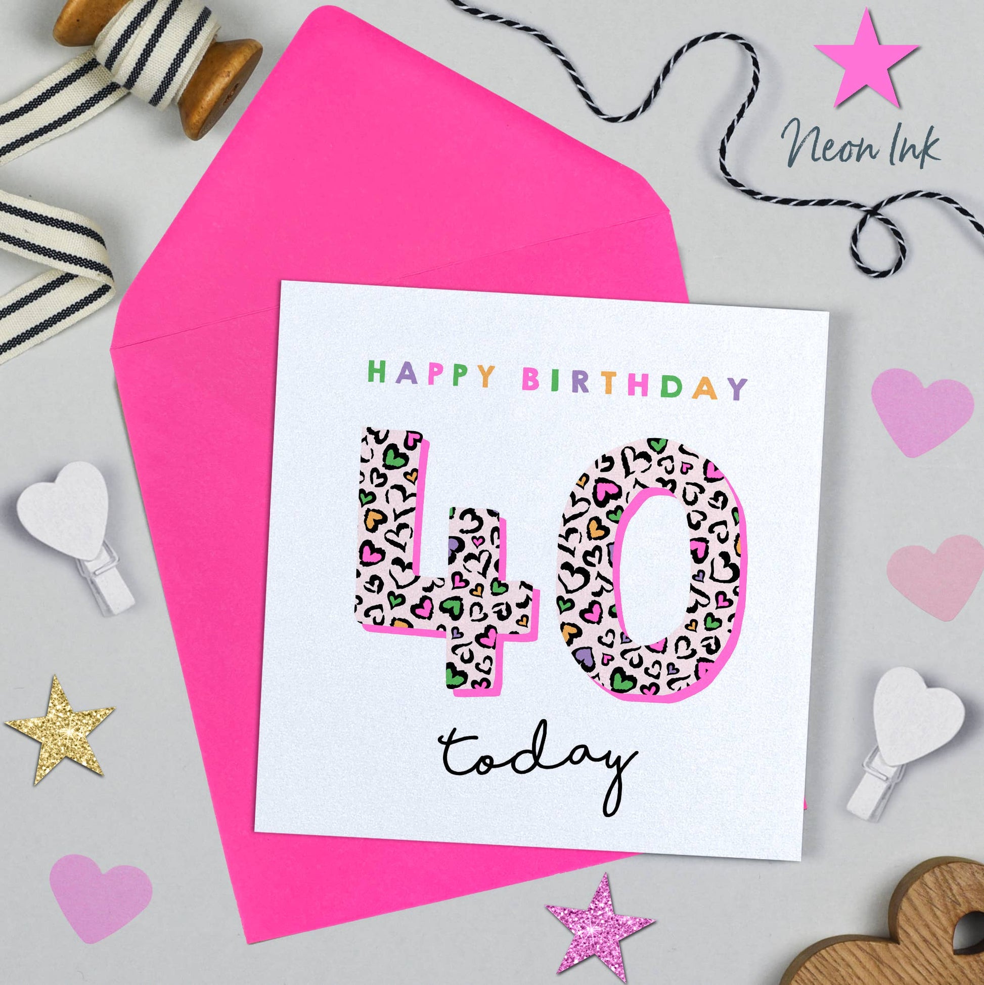 Happy Birthday card with leopard print number 40 on a pink envelope with decorative items around.