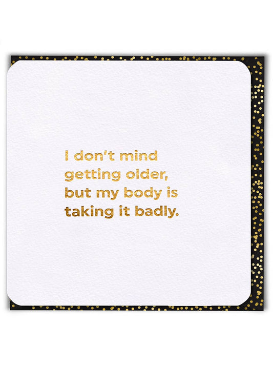 White card with gold text 'I don't mind getting older, but my body is taking it badly.' on a white background.