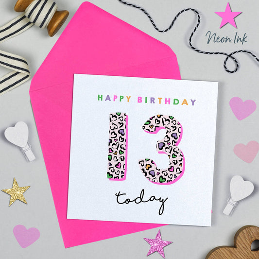 Birthday card with leopard print numbers '13' on a pink background with decorative items.