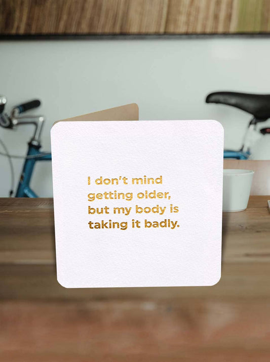 Card with humorous text on a wooden surface with bicycles in the background