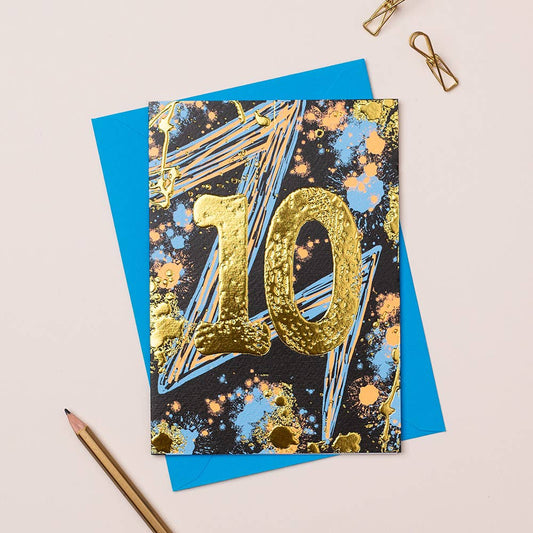 A card with an age 10 in gold foil and graffitti splatter