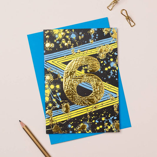 A greeting card with a gold foil 6 in the centre.