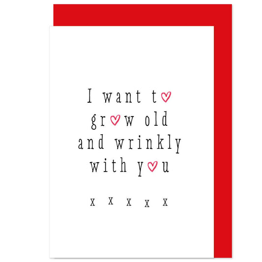 A greeting card with a white background and red envelope. The card has text that reads 'I WANT TO GROW OLD AND WRINKLY WITH YOU' in a vintage style font, accompanied by heart shapes.