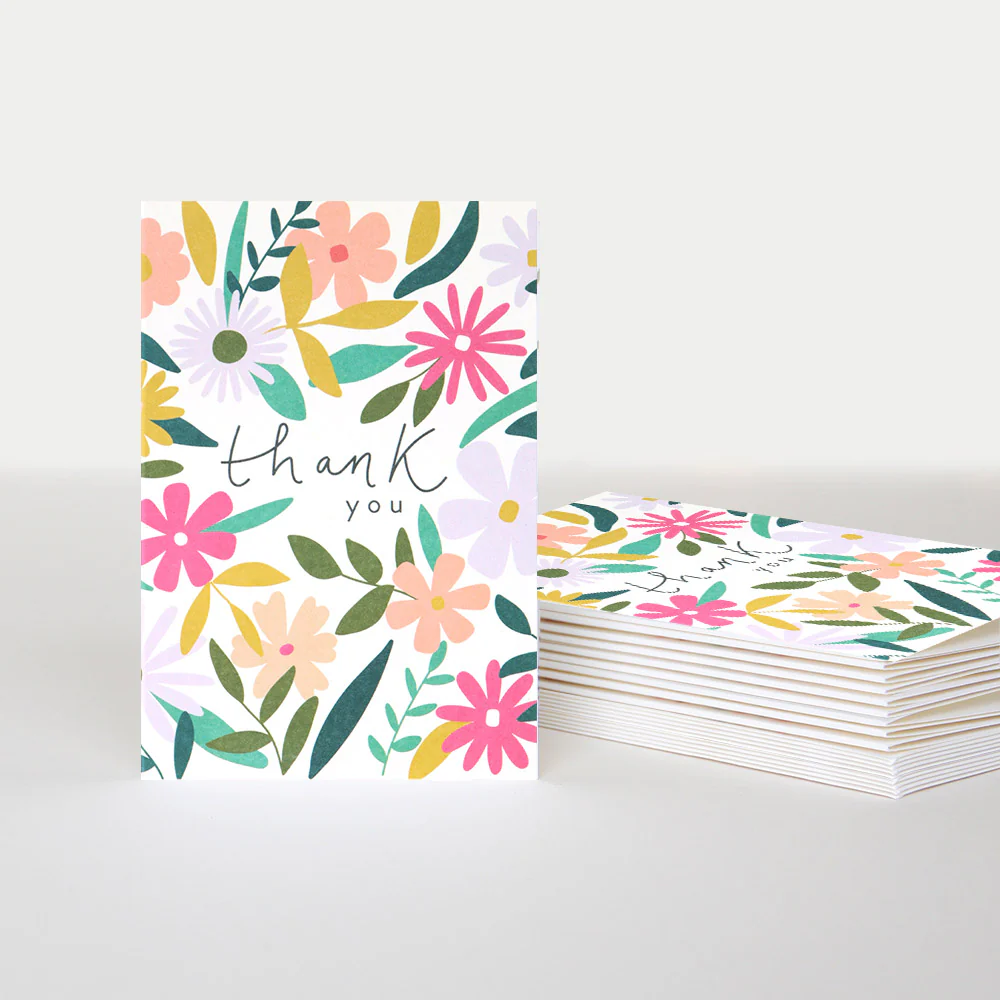 Floral card with 'thank you' text and a stack of similar cards on a light gray background
