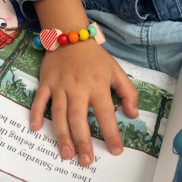 A small hand with a bracelet on, touching a book.