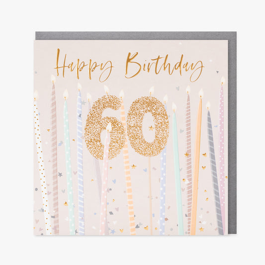 A cream card with tall candles and a gold 60 candle in the middle.  Gold writing saying "Happy Birthday" is at the top.  We can see a silver envelope inside.