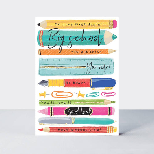 A colorful greeting card with illustrations of pencils, paper clips, and other stationery items, featuring biodegradable gold flitter and text celebrating a first day at school.