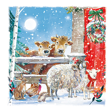 Winter scene with animals by a fireplace, including cows, sheep, and deer, with a gift box in the background.