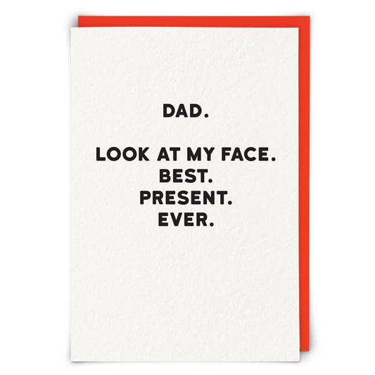 Greeting card with text 'DAD. LOOK AT MY FACE. BEST. PRESENT. EVER.' on a white background with a red border.