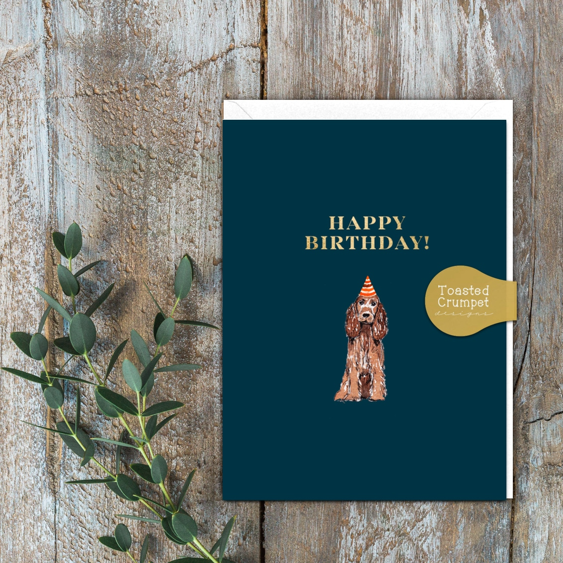 a BLUE GREETING CARD WITH A COCKER SPANIEL WITH A PARTY HAT. The words Happy Birthday.