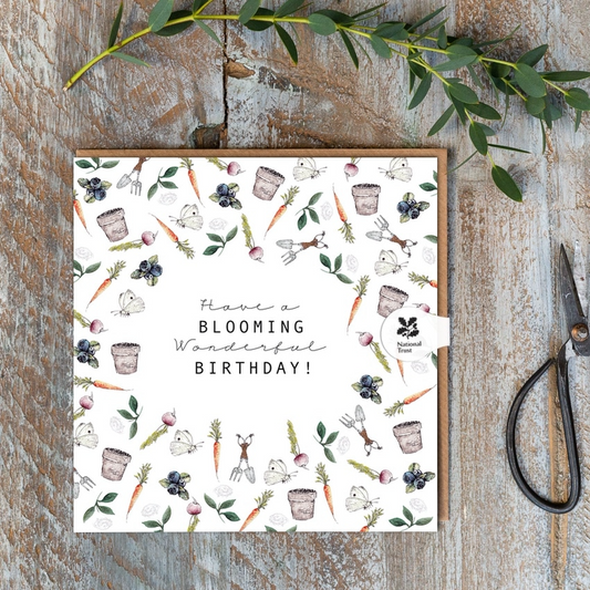 A white square card with plants, fruits and flowers framing the words "Have a Blooming Wonderful Birthday"