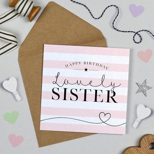 Birthday card for a sister with pink stripes and text on a gray background with decorative items.
