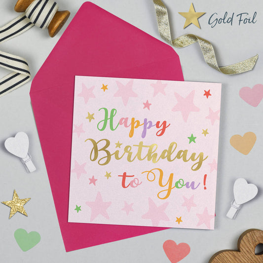 Happy Birthday card with pink envelope and decorative ribbons on a light gray background