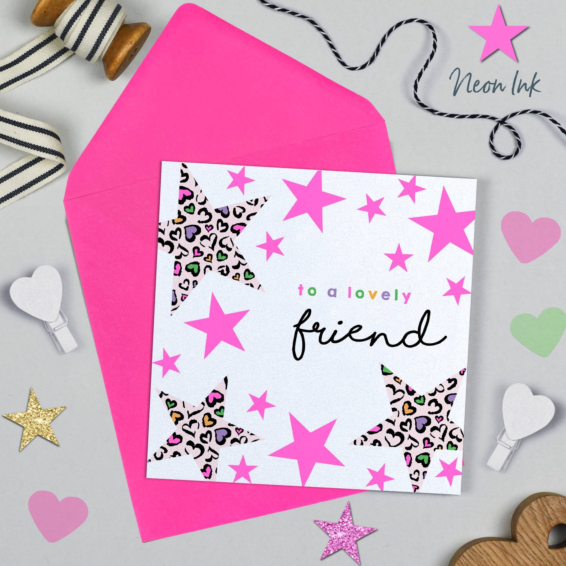 Greeting card with pink stars and 'to a lovely friend' text, surrounded by decorative items on a gray background.