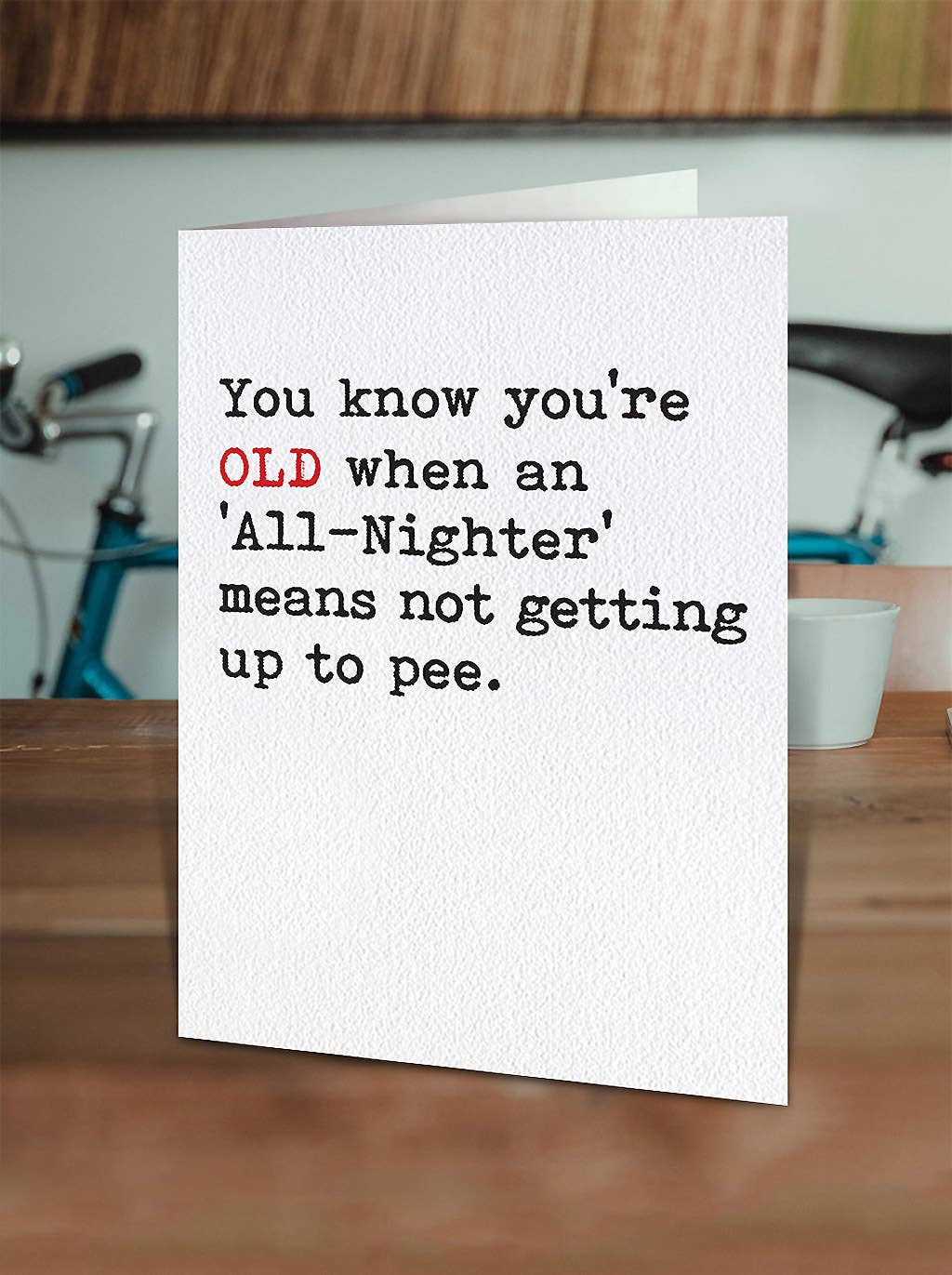 Card with humorous text on a wooden surface with a blurred background