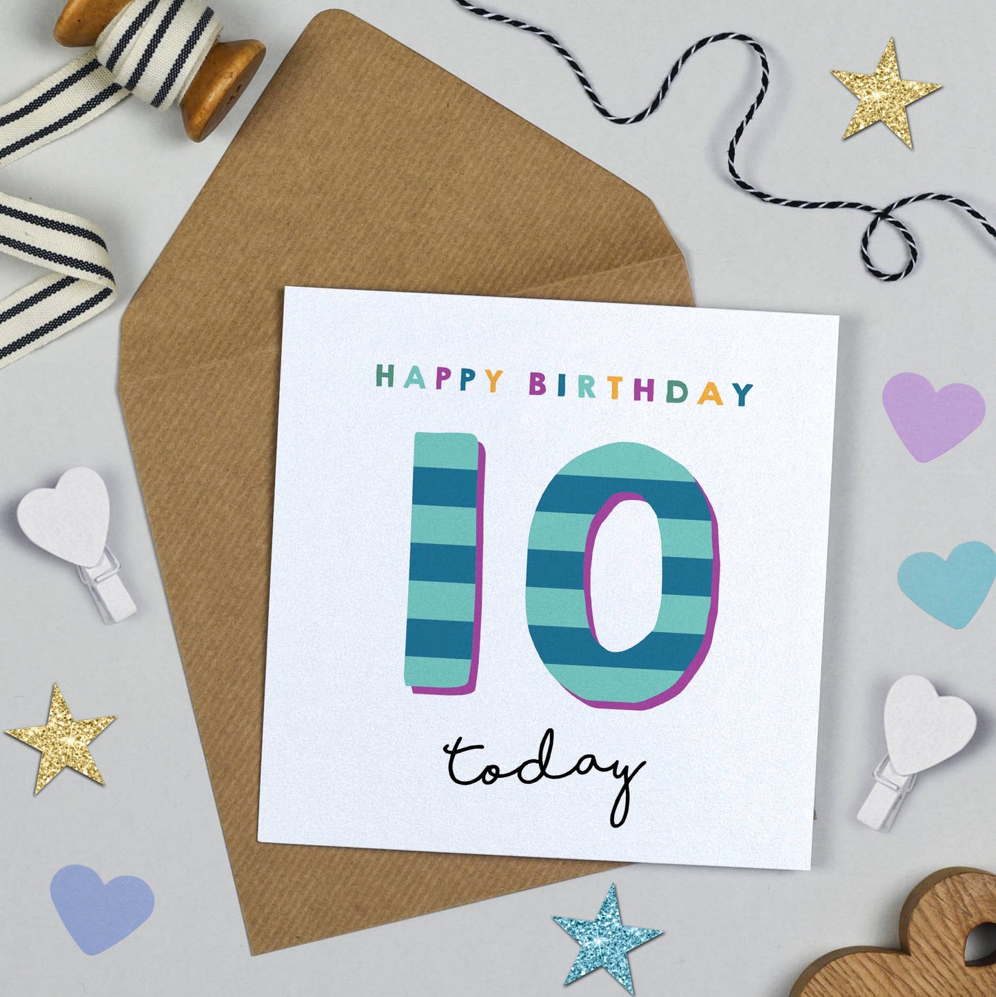 Birthday card with colorful number '10' on a textured surface with decorative items.