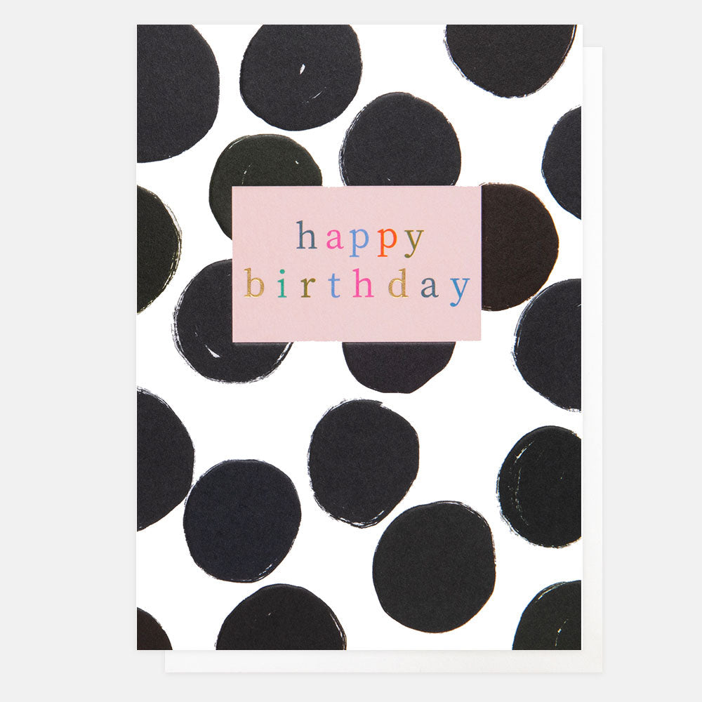 A white card with large black spots on it and a pink box with the words happy birthday in the centre of the card.