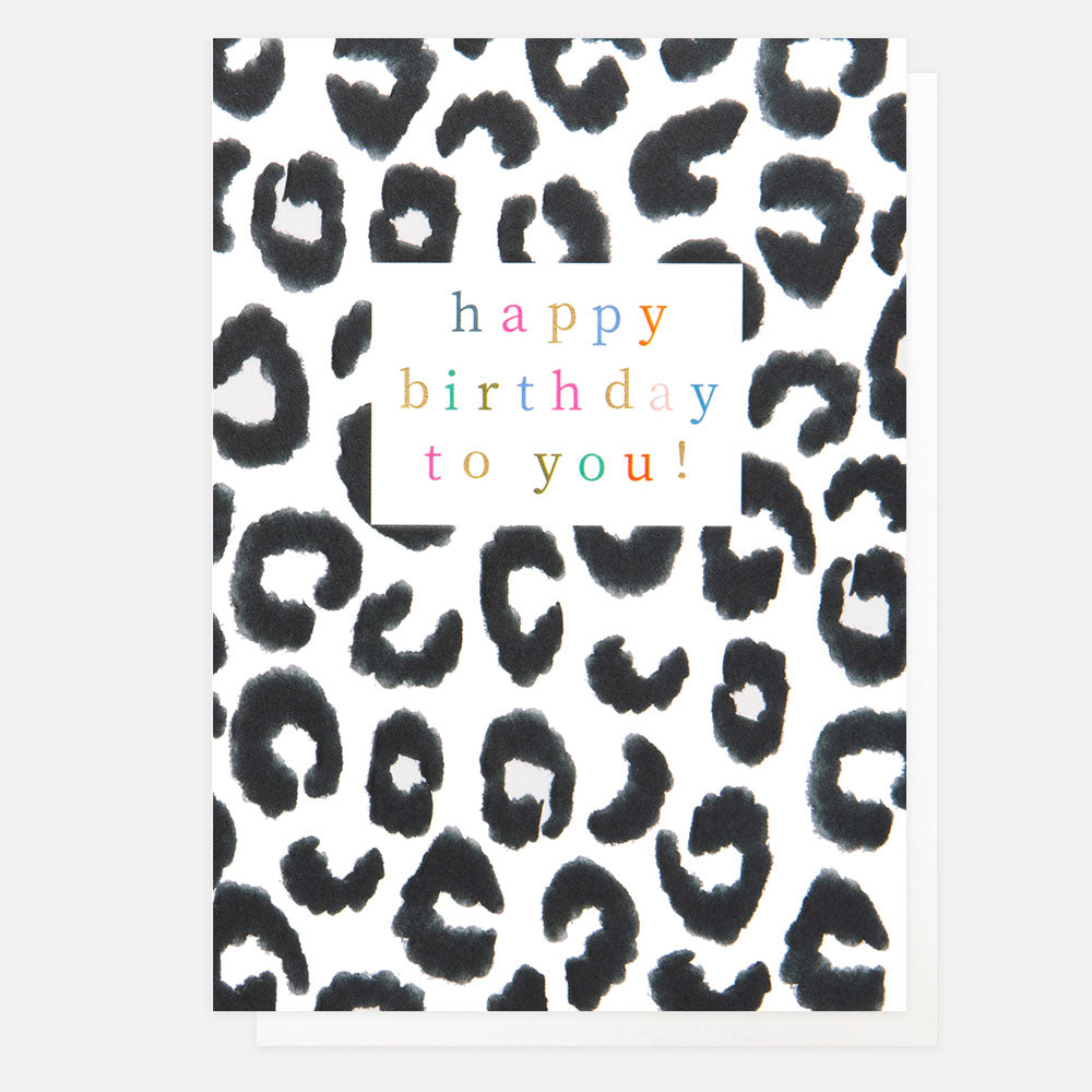 A white card with black leopard print spots and a white box with happy birthday to you in multi-coloured writing.