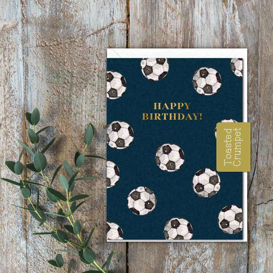 A small blue card with white and black footballs on and the words Happy Birthday.