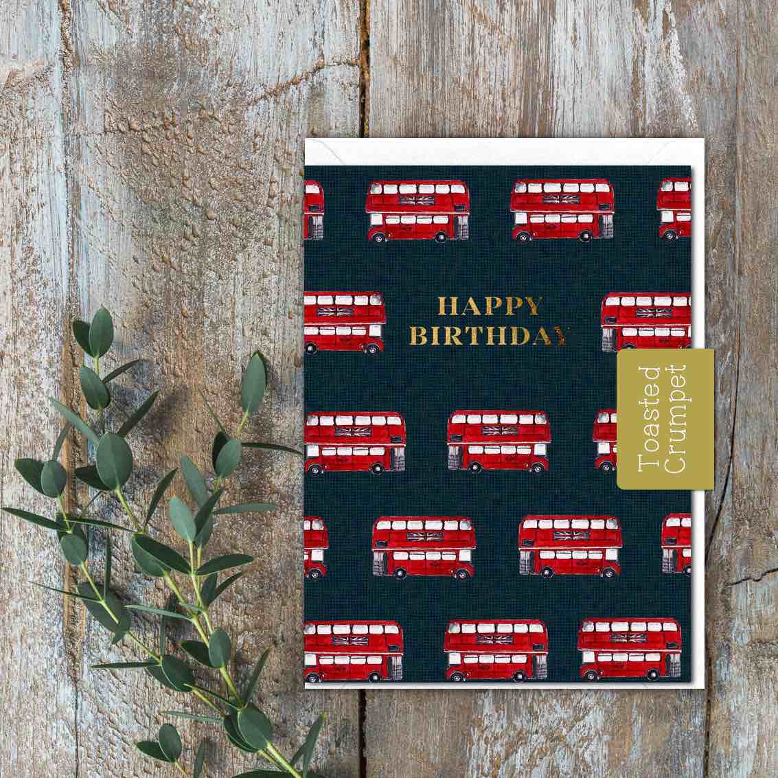 A small dark card with red London buses and a gold Happy Birthday