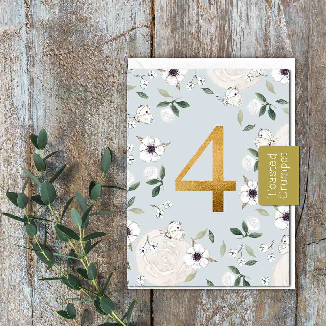 A page blue card with white flowers and a gold 4