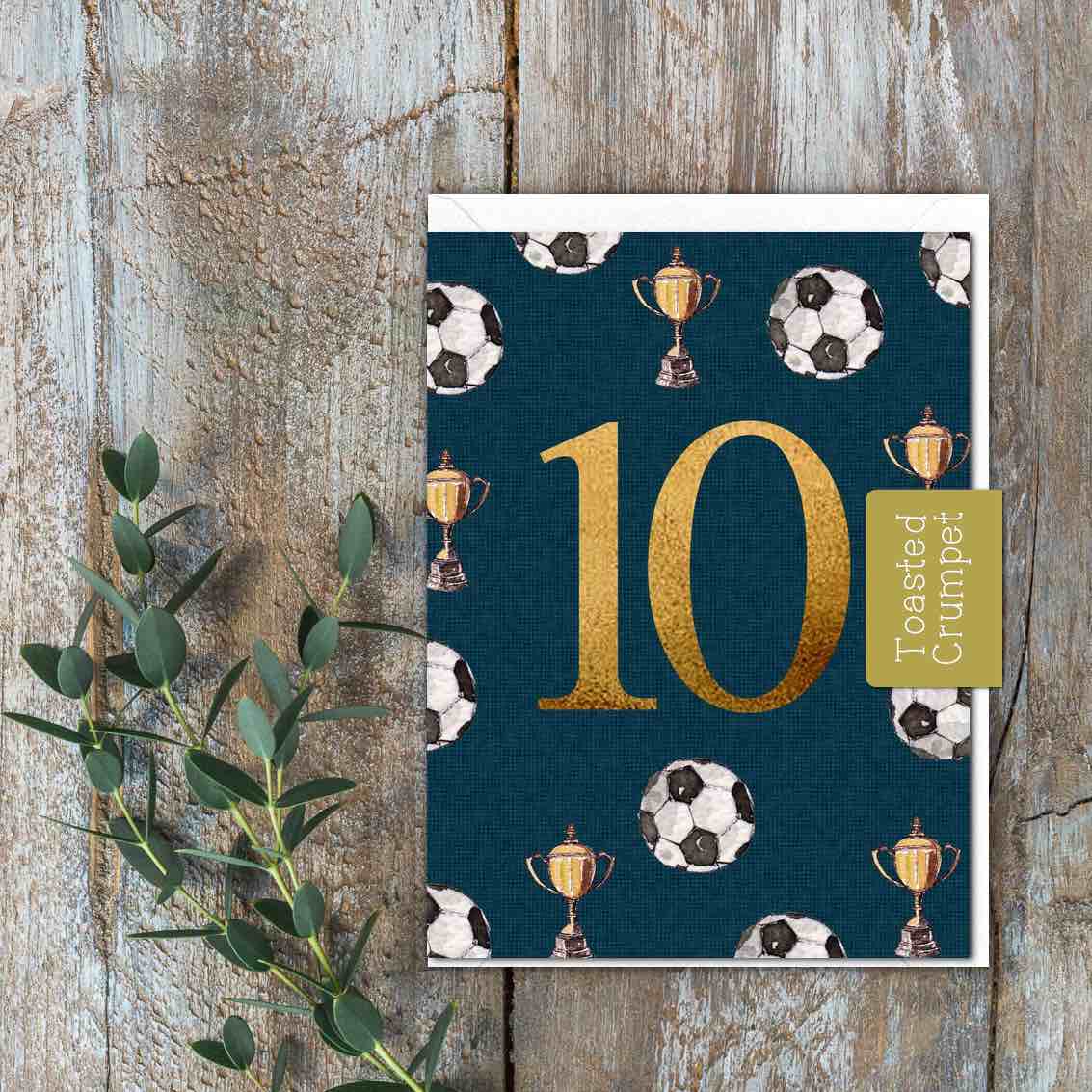 A dark blue/green card with 10 in the centre with footballs and a trophy 